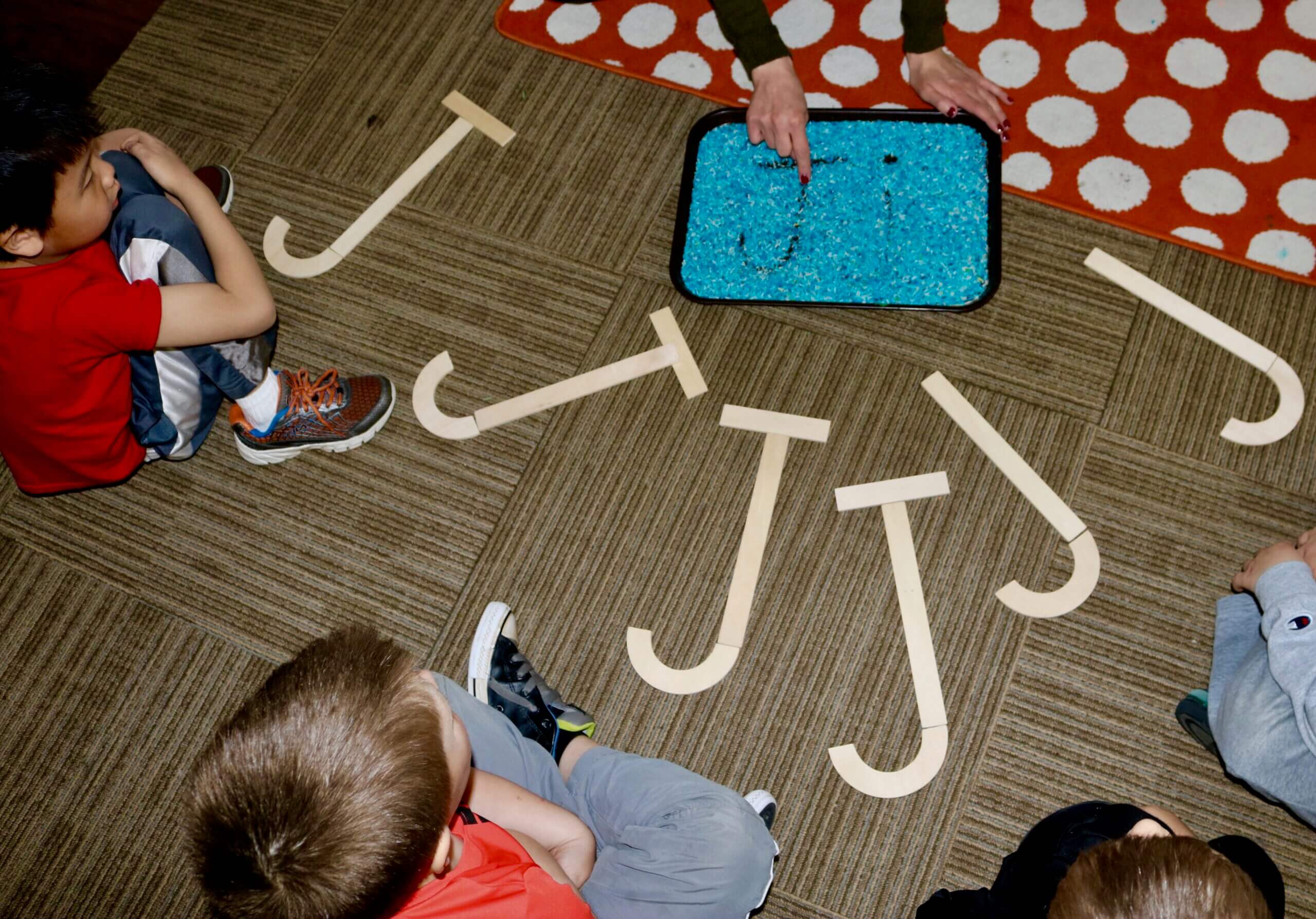 Example of sensory rice being used with the letter "J" with students of WCDS intensely looking on.